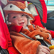 Lucas participe au concours pour gagner de l'argent avec cette photo : baby, child, car_seat, red, costume, fox, smiling, cute, fuzzy, hood, clothing, infant, seatbelt, hand, face, indoors, car, happy, portrait, young