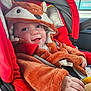 baby, child, car_seat, red, costume, fox, smiling, cute, fuzzy, hood, clothing, infant, seatbelt, hand, face, indoors, car, happy, portrait, young