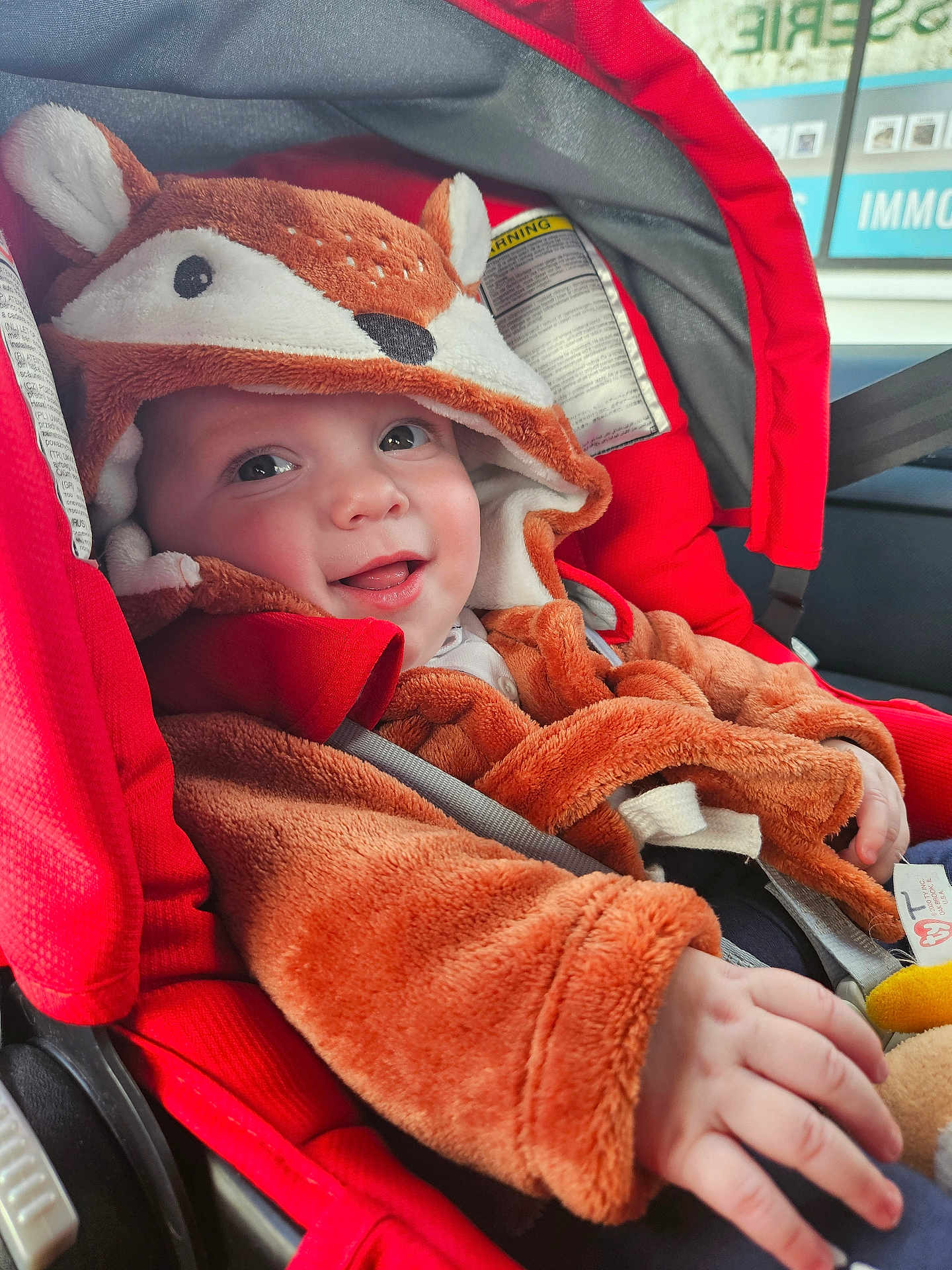 Lucas participe au concours pour gagner de l'argent avec cette photo : baby, child, car_seat, red, costume, fox, smiling, cute, fuzzy, hood, clothing, infant, seatbelt, hand, face, indoors, car, happy, portrait, young