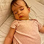 baby, sleeping, child, pink_clothing, quilted_background, peaceful, soft_light, infant, portrait, face, arm, bed, rest, calm, cute, indoors, young_child, closeup, relaxation, skin
