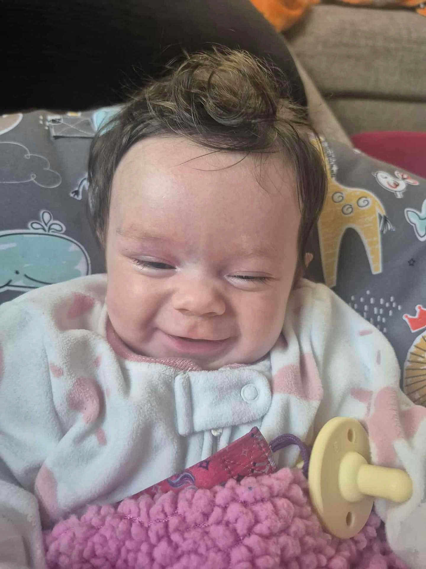 Abigail joined the competition — help win amazing prizes! baby, infant, smiling, pacifier, blanket, clothing, cute, face, person, indoors, cozy, soft, child, head, hair, pillow, pattern, animal_print, happy, resting