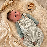 Sohan a rejoint le concours — aidez-le/la à gagner de superbes lots ! baby, bear_design, blanket, cozy, curious_expression, cute, dried_flowers, face, fluffy_rug, indoor, infant, laying_down, lion_illustration, one_month_old, overalls, portrait, socks, soft_texture, striped_clothing, wooden_sign