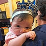 Dahlia is registered to the contest to win money with this photo: baby, child, headband, star, numbers, indoor, kitchen, person, holding, face, curious, clothing, hair, adult, shoulder, home, portrait, cute, expression, celebration