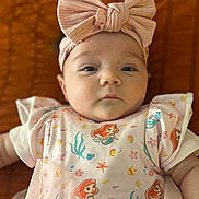 Dahlia is registered to the contest to win money with this photo: baby, infant, headband, bow, pink, dress, cartoon, mermaid, pattern, face, portrait, child, closeup, cute, expression, clothing, soft, texture, background, lying_down
