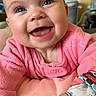 baby, smiling, pink_clothing, teething_toy, cushion, indoor, happy, child, infant, face, portrait, cute, cozy, soft_texture, home, playful, young_child, expression, closeup, person