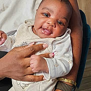Iris participe au concours pour gagner de l'argent avec cette photo : baby, child, person, infant, smile, face, hand, clothing, sleeve, arm, watch, bracelet, holding, seated, portrait, indoor, cute, happy, warm, closeup