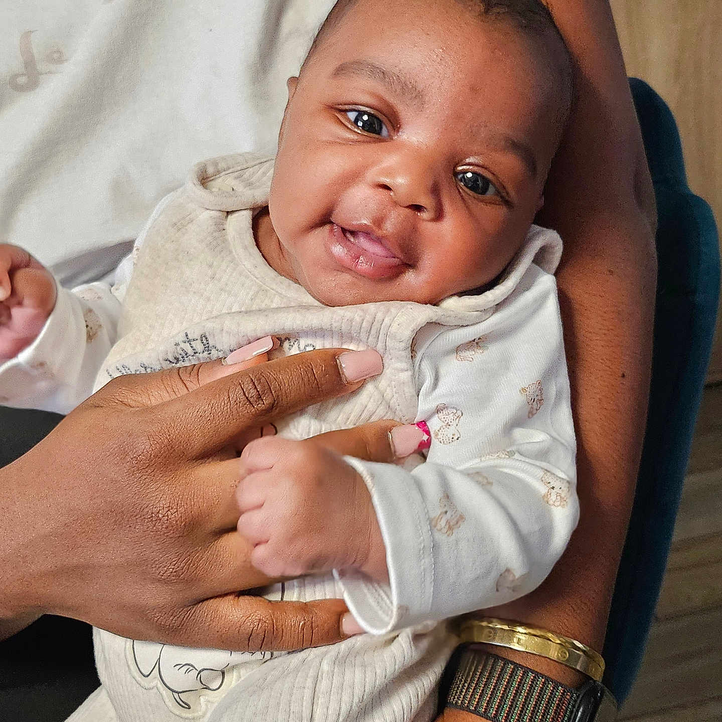 Iris participe au concours pour gagner de l'argent avec cette photo : arm, baby, bracelet, child, closeup, clothing, cute, face, hand, happy, holding, indoor, infant, person, portrait, seated, sleeve, smile, warm, watch