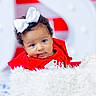 Alayah is registered to the contest to win money with this photo: baby, child, face, bow, curly_hair, red_clothing, blanket, fluffy, portrait, cute, infant, smiling, indoors, soft_texture, closeup, person, headwear, young, expression, colorful_background