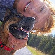 Katie is registered to the contest to win money with this photo: woman, dog, outdoor, sunlight, smile, happy, pet, nature, gravel_path, trees, sunflare, closeup, collar, hand, portrait, red_collar, casual_clothing, short_hair, daylight, affection