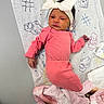 A Zarah joined the competition — help win amazing prizes! baby, newborn, pink_clothing, headband, white_bow, blanket, animal_doodles, lying_down, infant, patterned_paper, soft_texture, cute, indoors, child, portrait, baby_girl, small_hand, baby_sock, cozy, resting