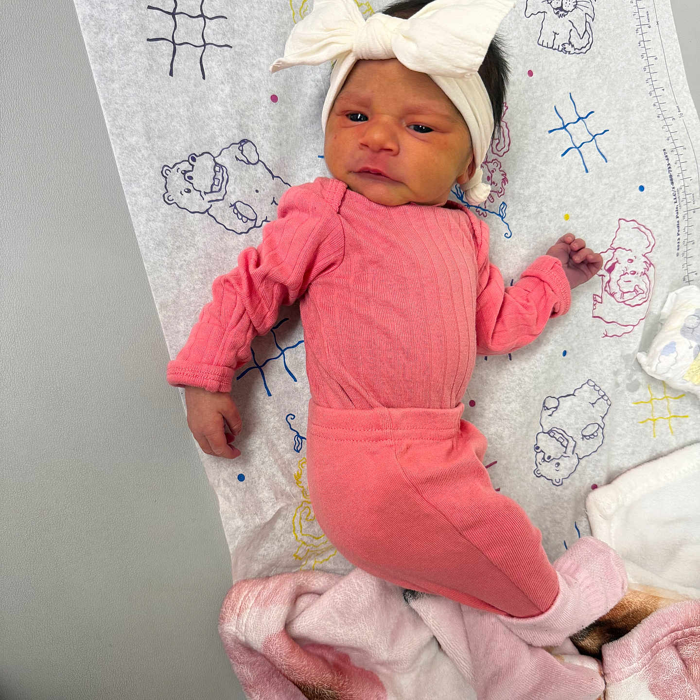 A Zarah joined the competition — help win amazing prizes! baby, newborn, pink_clothing, headband, white_bow, blanket, animal_doodles, lying_down, infant, patterned_paper, soft_texture, cute, indoors, child, portrait, baby_girl, small_hand, baby_sock, cozy, resting