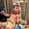 A Zarah is registered to the contest to win money with this photo: newborn, baby, hospital, medical, infant, diaper, gloved_hand, headband, pink_bow, vernix, monitor, medical_equipment, person, closeup, child, skin, healthcare, delivery_room, freshly_born, cute