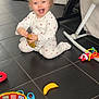 toddler, child, pajamas, indoor, floor, toy, smile, happy, play, colorful, plastic_toy, banana_toy, steering_wheel_toy, baby, crawling, joyful, girl, puzzle_toy, home, cute