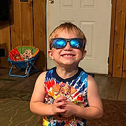 Cyrus joined the competition — help win amazing prizes! child, boy, sunglasses, smile, indoor, paw_patrol, tank_top, wood_paneling, door, carpet, chair, toy, happy, portrait, casual, furniture, reflection, colorful, cute, hands