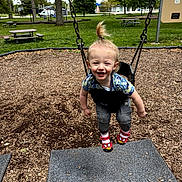 Kolsen joined the competition — help win amazing prizes! toddler, child, swing, playground, park, grass, trees, picnic_table, shoes, clothing, smiling, happy, hair, topknot, outdoor, fun, woodchips, daylight, person, recreation