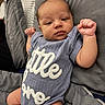 Jhire is registered to the contest to win money with this photo: baby, infant, onesie, clothing, bed, pillow, blanket, face, fist, skin, person, newborn, cute, lying_down, sleepwear, text_on_clothing, indoor, soft, rest, portrait