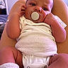Jhire joined the competition — help win amazing prizes! baby, infant, pacifier, white_onesie, socks, blue_stripes, lap, skin, hand, face, legs, indoor, person, clothing, newborn, cute, expression, human, resting, comfort