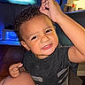 Jaden joined the competition — help win amazing prizes! child, toddler, curly_hair, smiling, indoor, television, blue_light, hand, face, shirt, black_shirt, skin, couch, wood_floor, living_room, person, young_child, cute, happy, playful