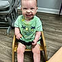 Ronyn is registered to the contest to win money with this photo: baby, child, smiling, green_shirt, wooden_chair, messy, food, floor, indoor, happy, cute, sitting, toddler, playful, face, legs, ears, short_hair, wood, chair
