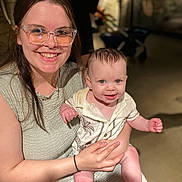 Ronyn is registered to the contest to win money with this photo: baby, child, woman, glasses, smile, happy, holding, indoor, portrait, person, clothing, face, skin, hair, young, casual, seated, light, focus, background_blur