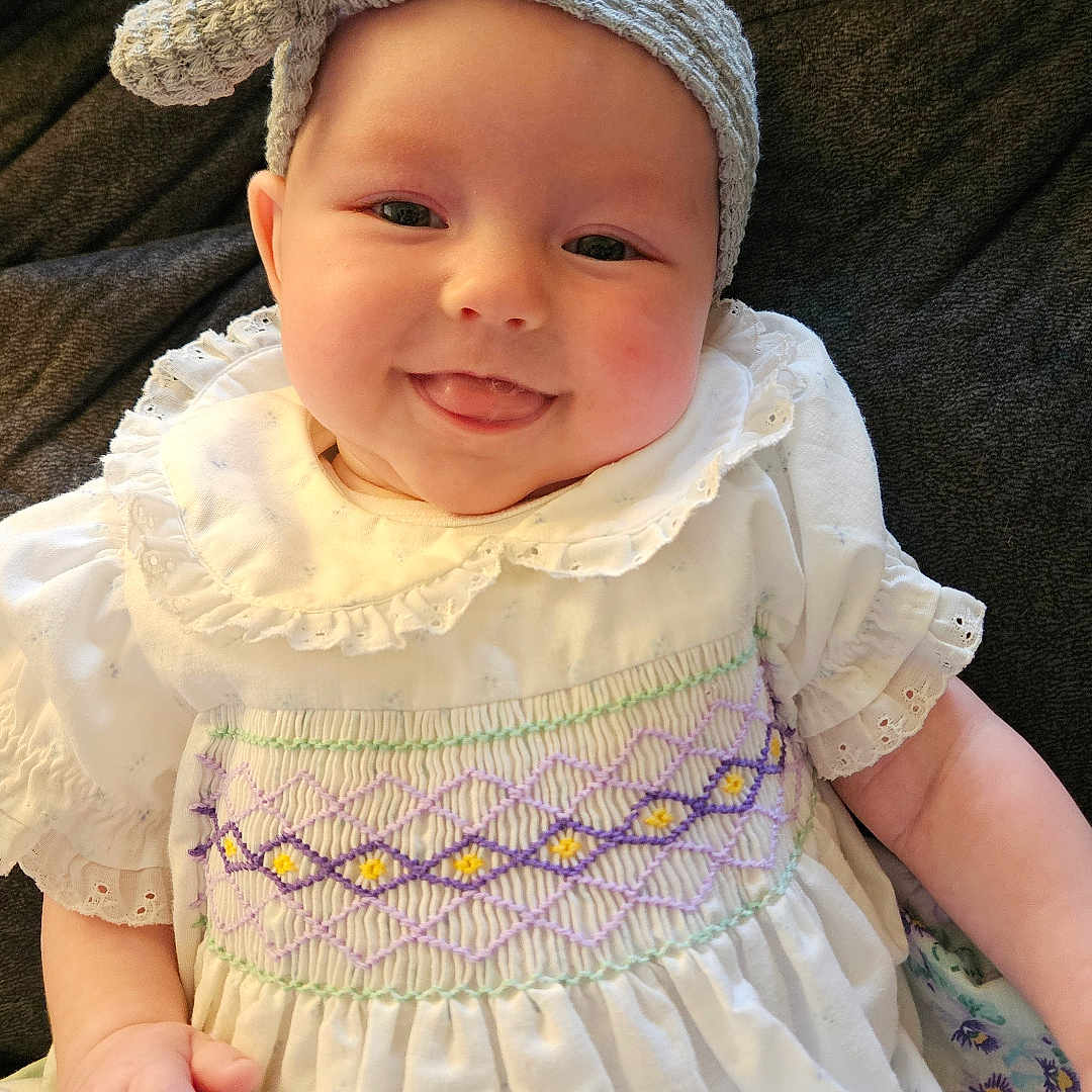 Ember joined the competition — help win amazing prizes! baby, beanie, bonnet, cap, clothing, couch, dress, face, happy, hat, head, homedecor, linen, newborn, pants, person, photography, portrait, sitting, smile