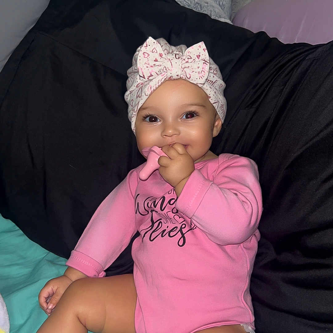Ivori Jane Blakeley joined the competition — help win amazing prizes! baby, bed, blanket, child, cute, face, foot, hand, happy, headwrap, indoor, infant, person, pillow, pink_onesie, sitting, skin, smiling, sock, teething_toy