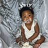 Janayah is registered to the contest to win money with this photo: baby, cake, celebration, child, colorful_cake, cute, face_paint, festive, frosting, hands, happy, headband, indoors, messy, party, portrait, silver_streamers, sitting, smiling, white_clothing