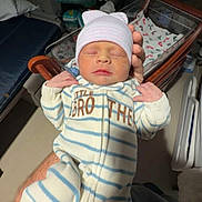 Stetson joined the competition — help win amazing prizes! newborn, baby, infant, sleeping, hat, onesie, striped_clothing, hospital, crib, blanket, hand, adult, bed, baby_clothes, person, indoor, soft_lighting, cute, peaceful, family