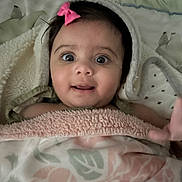 Radha is registered to the contest to win money with this photo: baby, child, blanket, pink_bow, wide_eyes, wrapped, cozy, cute, infant, portrait, indoor, soft_texture, smiling, expression, head, face, skin, hand, person, toddler