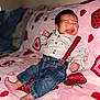 baby, infant, crying, denim, suspenders, striped_shirt, pink_blanket, strawberry_pattern, clothing, cute, indoors, furniture, person, face, foot, hand, expression, child, newborn, soft_texture