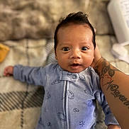 Ivan joined the competition — help win amazing prizes! baby, infant, newborn, face, wide_eyes, blue_onesie, tattooed_arm, arm, hand, hair, blanket, plaid_pattern, bed, baby_bottle, soft_bokeh, portrait, skin, smile, lying_down, cozy