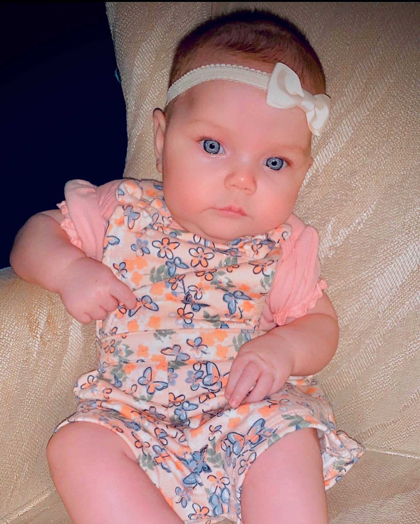 Emma is registered to the contest to win money with this photo: baby, baby_toddler_clothing, cheek, child, day_dress, dress, eye, headwear, human_body, human_leg, iris, lip, neck, nose, organ, pattern, person, pink, skin, sleeve
