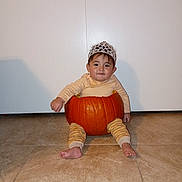 Valerie is registered to the contest to win money with this photo: baby, infant, pumpkin, halloween, costume, crown, sitting, floor, indoor, portrait, child, face, expression, clothing, orange, autumn, celebration, home, photography, cute