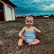 Louise a rejoint le concours — aidez-le/la à gagner de superbes lots ! baby, child, grass, outdoor, smile, blue_outfit, house, sky, cloudy, sitting, barefoot, nature, field, portrait, person, young_child, summer, grass_lawn, playful, daylight