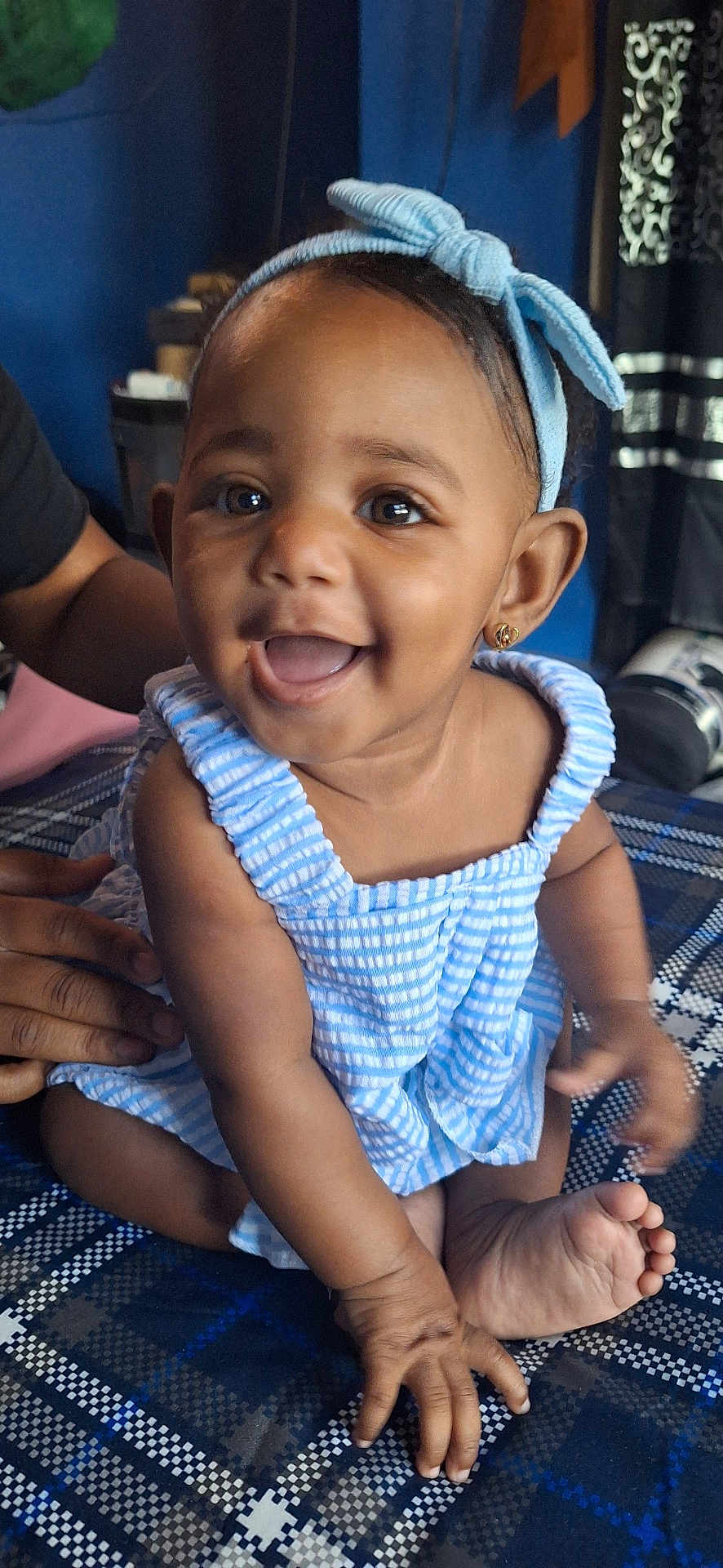 Mei'Lanii joined the competition — help win amazing prizes! baby, child, smiling, happy, blue_dress, headband, earrings, sitting, hands, feet, person, indoor, patterned_surface, cute, infant, portrait, skin, face, eyes, mouth