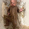 Logan is registered to the contest to win money with this photo: baby, infant, child, portrait, lying_down, bassinet, crib, blanket, sleepwear, brown_outfit, face, eyes, hands, raised_hand, serious_expression, indoor, nursery, patterned_bedding, cozy, photography