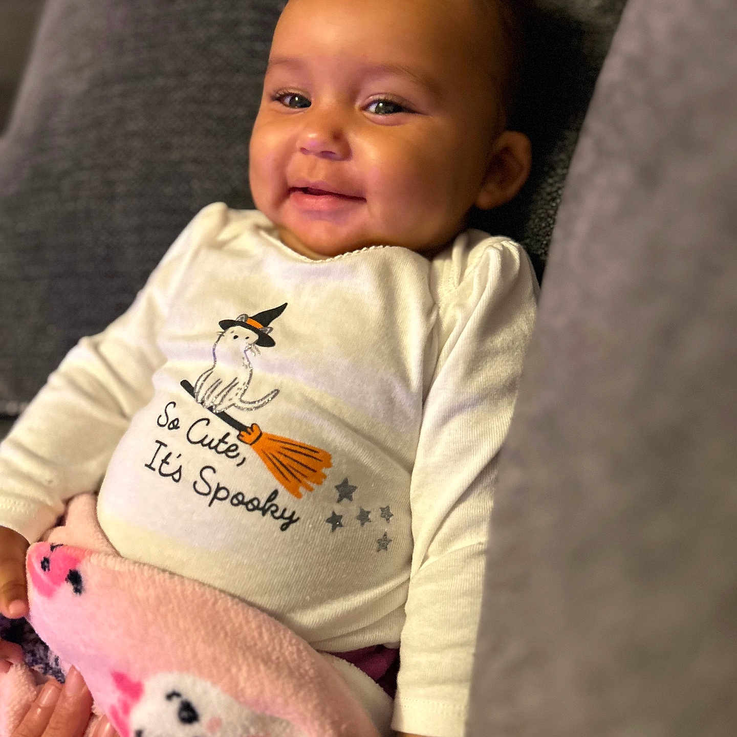 Mo'Hana is registered to the contest to win money with this photo: baby, blanket, broom, child, clothing, couch, cozy, cute, halloween, hand, happy, indoor, infant, person, pink, portrait, shirt, smiling, stars, witch_hat
