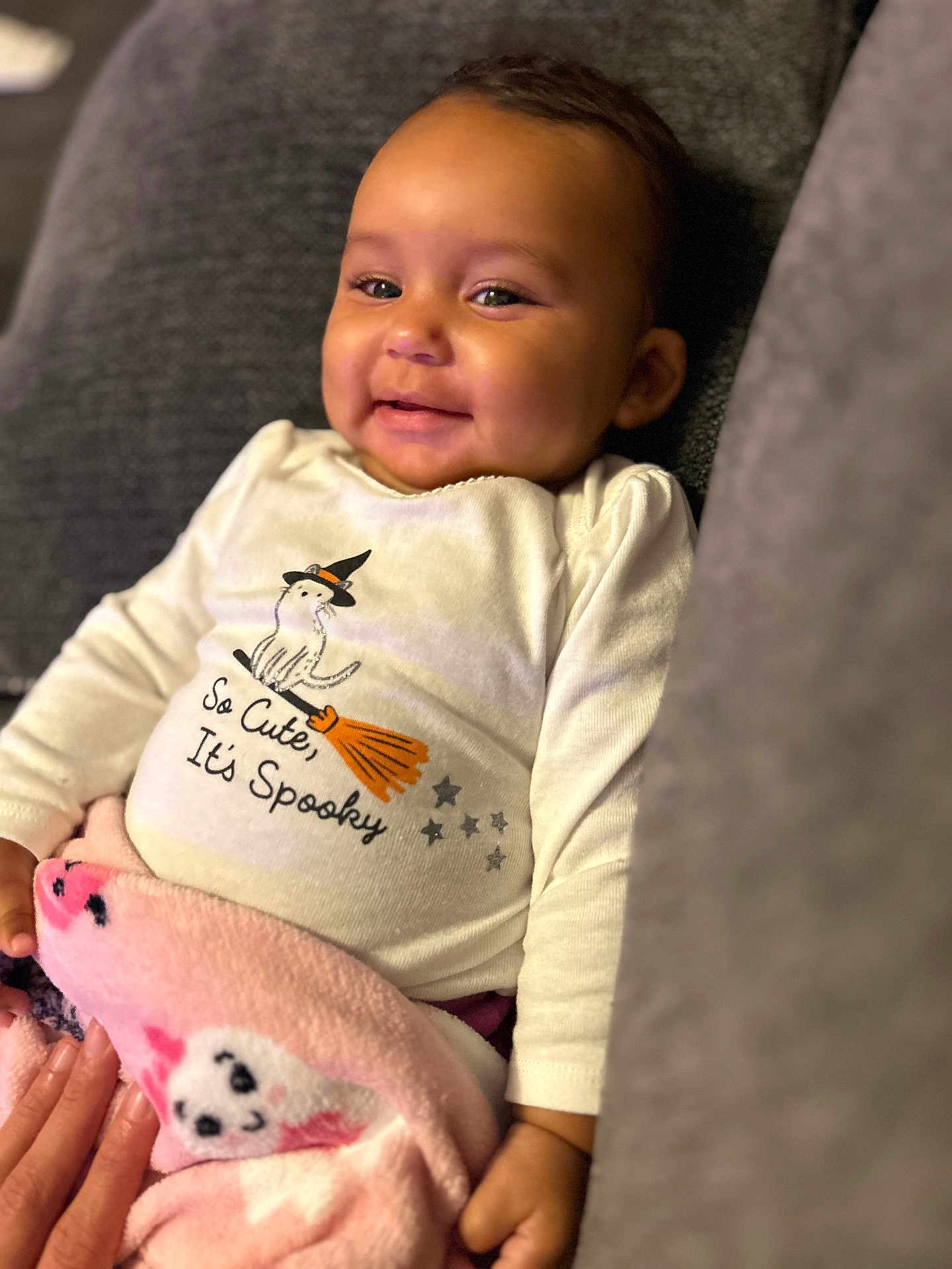 Mo'Hana is registered to the contest to win money with this photo: baby, smiling, infant, blanket, pink, cute, shirt, halloween, witch_hat, broom, stars, indoor, couch, cozy, child, happy, portrait, clothing, person, hand