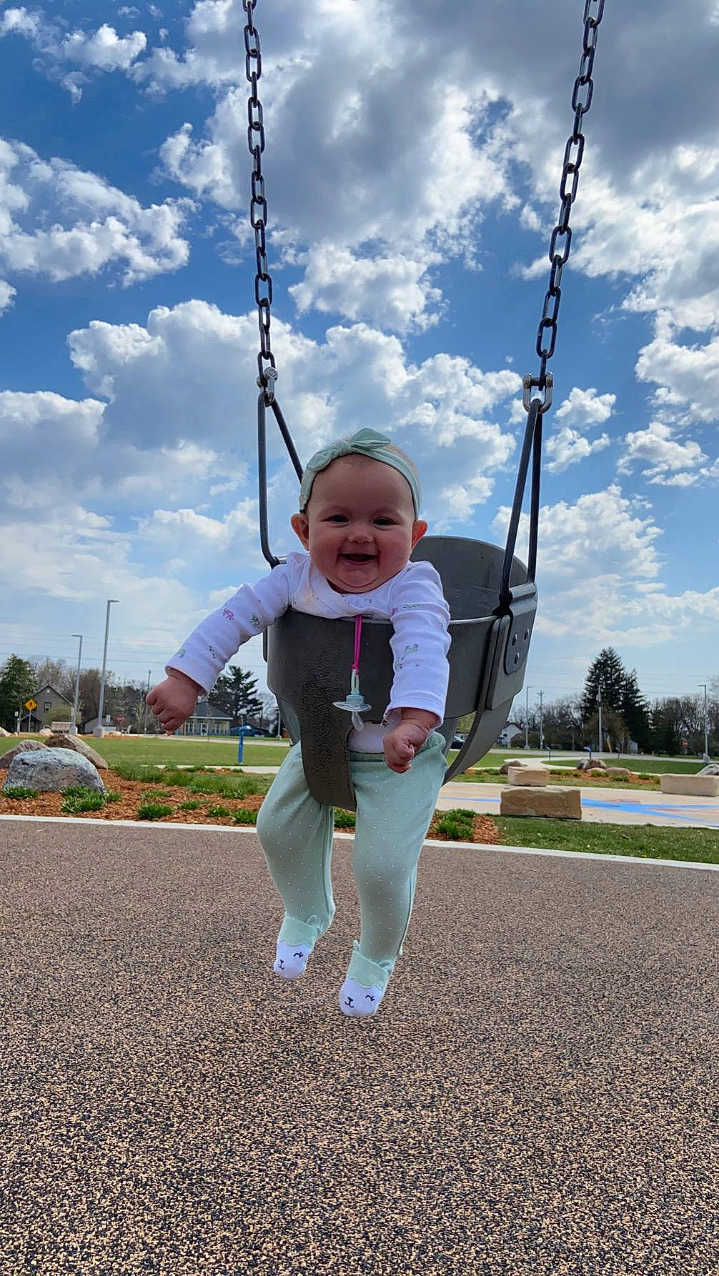 Ila is registered to the contest to win money with this photo: asphalt, baby, city, cloud, electric_blue, fun, grass, happy, joy, leisure, outdoor_play_equipment, person, plant, playground, public_space, recreation, sky, sleeve, smile, swing