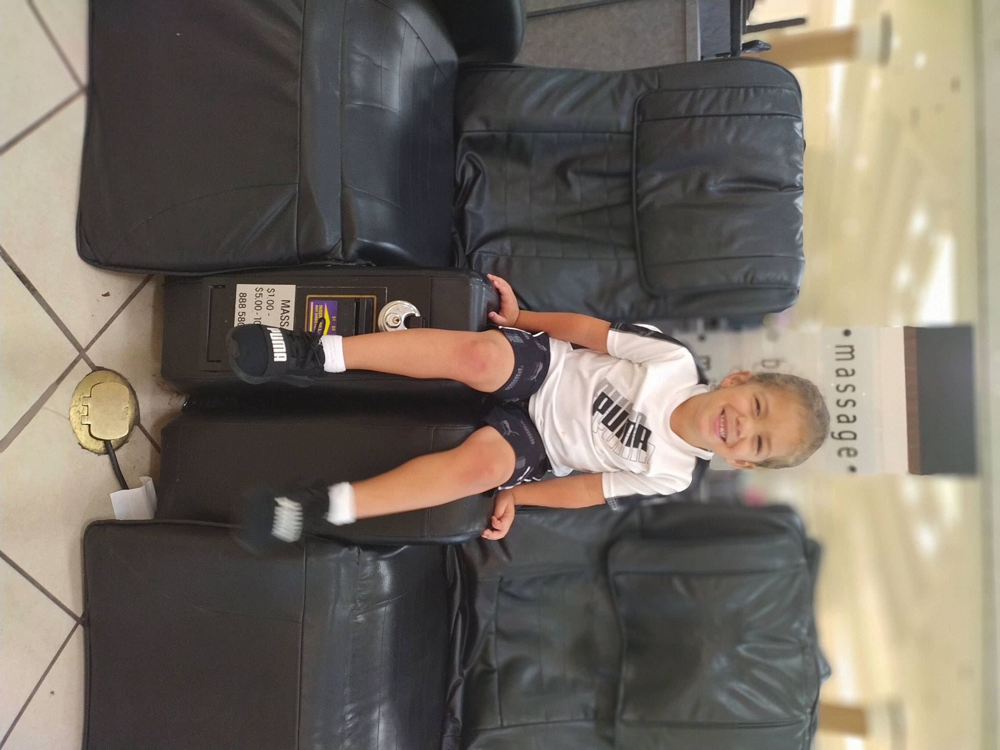 Liam is registered to the contest to win money with this photo: auto_part, bag, baggage, comfort, elbow, fun, human_leg, joy, knee, luggage_and_bags, person, room, shorts, sitting, smile, suitcase, t_shirt, thigh, wrist