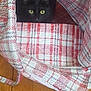 black_cat, cat, pet, animal, indoor, bag, checkered_pattern, fabric, wooden_floor, curious, peeking, yellow_eyes, cozy, domestic_cat, feline, resting, close_up, hidden, zipper, texture