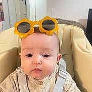 Emma participe au concours pour gagner de l'argent avec cette photo : baby, child, sunglasses, yellow, flower_shaped, knitted_sweater, beige_seat, harness, indoor, neutral_expression, face, person, young_child, cute, clothing, headwear, seat, baby_seat, closeup, young_baby