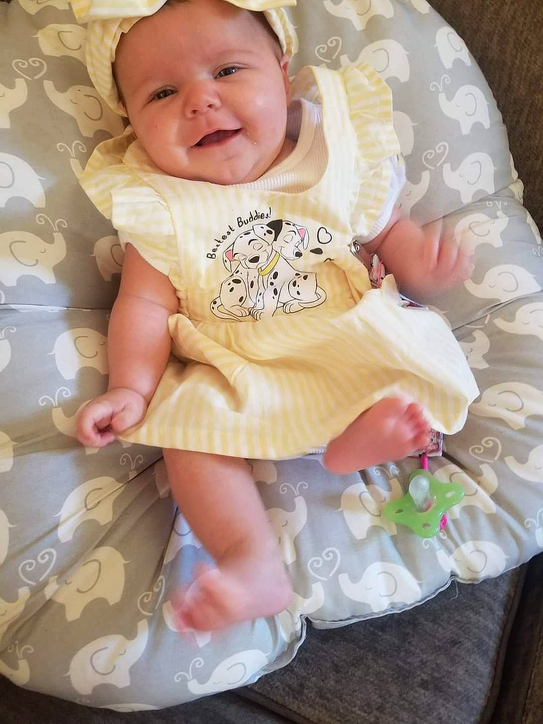 Loretta is registered to the contest to win money with this photo: baby, baby_toddler_clothing, cheek, child, comfort, eye, fashion_accessory, happy, headgear, joy, linens, pattern, peach, person, pink, product, sitting, skin, sleeve, smile