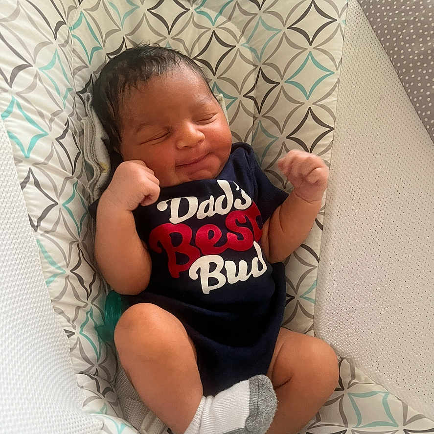 Asante joined the competition — help win amazing prizes! newborn, baby, infant, smiling, onesie, socks, baby_seat, patterned_fabric, indoor, cute, resting, peaceful, child, person, portrait, small, cozy, happy, relaxed, clothing