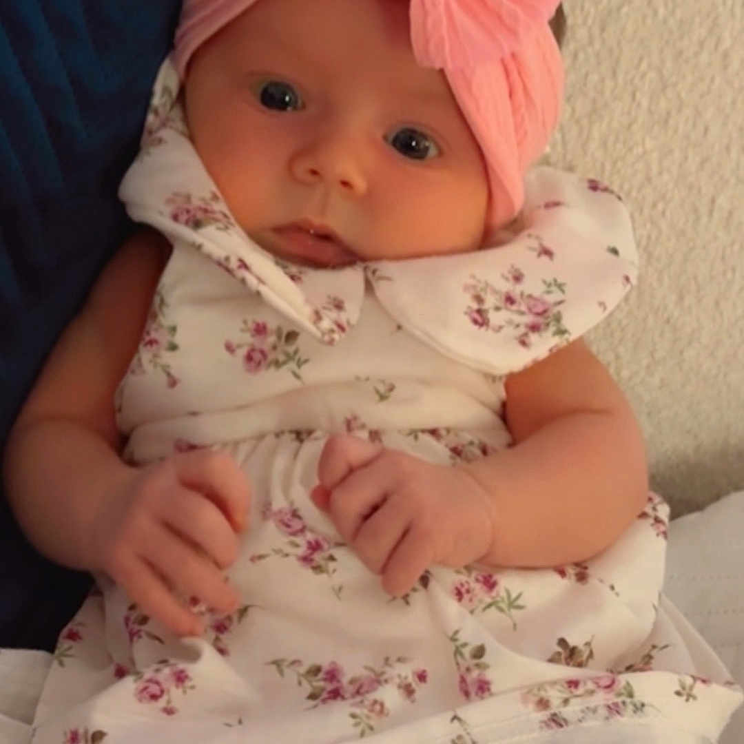 Pearly joined the competition — help win amazing prizes! adorable, baby, blanket, child, clothing, cushion, cute, expression, face, floral_dress, hands, headband, indoors, infant, legs, pink_bow, portrait, sitting, soft_lighting, young