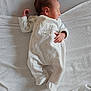 baby, newborn, infant, sleeping, bed, pillow, blanket, onesie, clothing, white, peaceful, hand, side_profile, portrait, soft_texture, footed_pajamas, nursery, cozy, crib_bedding, relaxation
