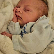 Maëlyo a rejoint le concours — aidez-le/la à gagner de superbes lots ! baby, newborn, infant, sleeping, blanket, bedding, swaddle, hand, face, cheek, soft_texture, cozy, portrait, close_up, indoor, nursery, peaceful, plush, warm_tone, camera_watermark