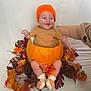 Oscar is registered to the contest to win money with this photo: baby, pumpkin, autumn_leaves, pine_cones, orange_hat, smiling, socks, fall_decor, cute, child, seasonal, knitted_hat, hand, person, holiday, celebration, indoors, decoration, happy, festive
