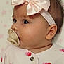 baby, infant, pacifier, headband, bow, pink, white_clothing, hearts, blanket, stars, face, profile, cute, sleepwear, child, newborn, soft_texture, adorable, lying_down, indoors