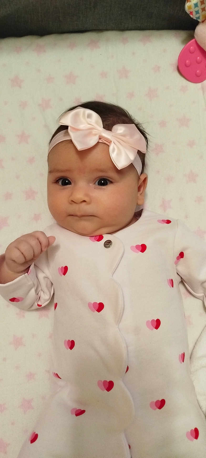 Gloria participe au concours pour gagner de l'argent avec cette photo : baby, infant, onesie, headband, bow, heart_pattern, blanket, star_pattern, cute, face, expression, clothing, sleepwear, lying_down, indoor, child, adorable, soft_toys, pink, white